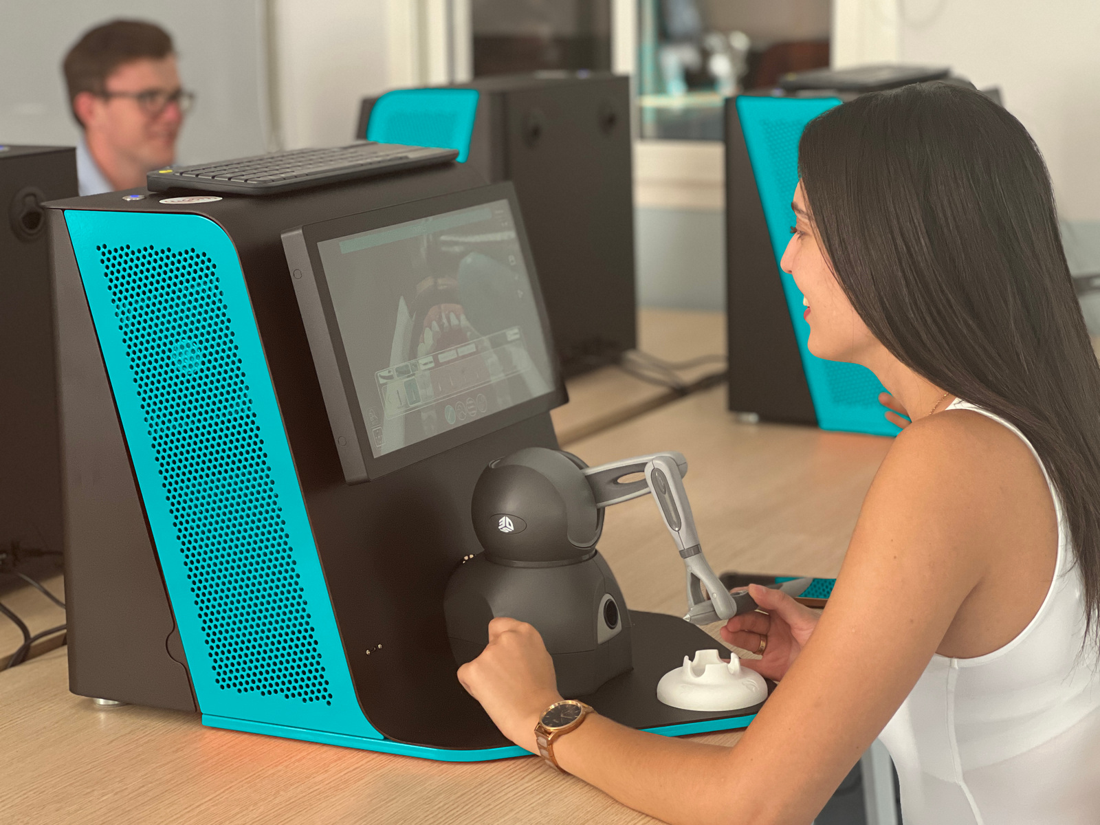 A student smiling while using Virteasy Desktop with its haptic arm