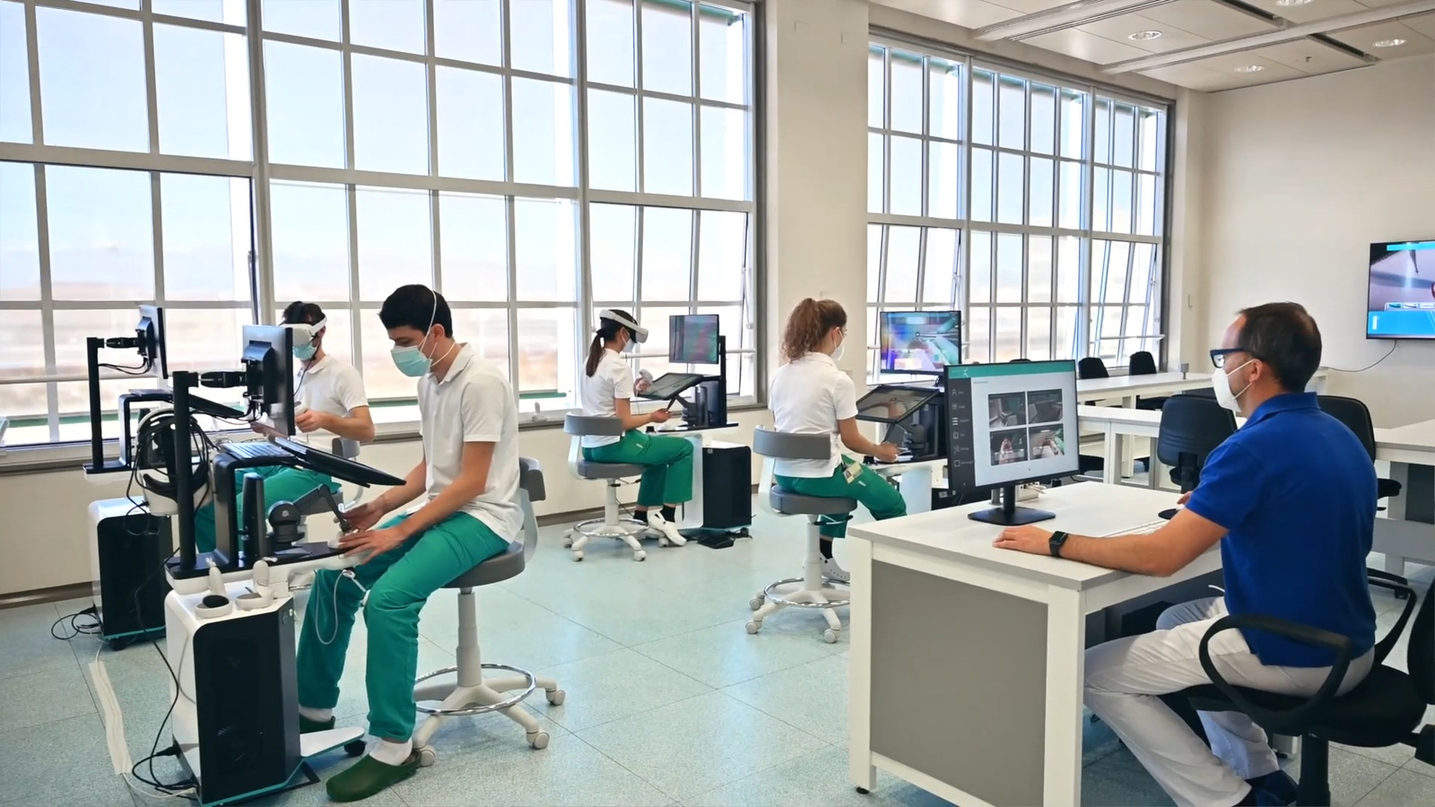 Students practising on Virteasy workstations while a teacher monitors from his desk at the University of Turin